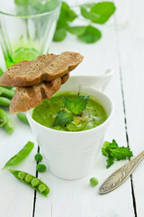 Green pea soup with croutons on wooden rustic background