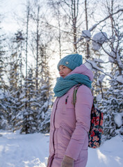 A girl in a red jacket walks through a snow-covered forest