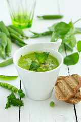Green pea soup with croutons on wooden rustic background