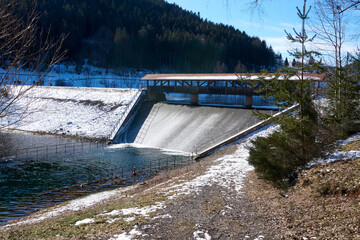 dam on a winter river with snow and ice under a blue sky