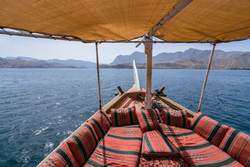 View fom the traditional arabian dhow boat sailing on the sea. Red pillows and carpets, yellow fabric shade.