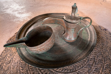 Vintage Brass Ornate Arabic Dallah. Metal tea pot on a metal plate.