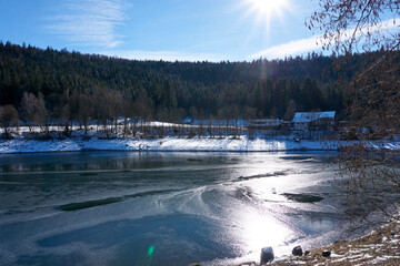 partially frozen river with snow and ice under a blue sky