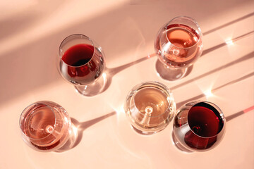 Glasses of red, rose and white wine with sunshine shadow effect. Concept of wine tasting. Flat lay, top view.