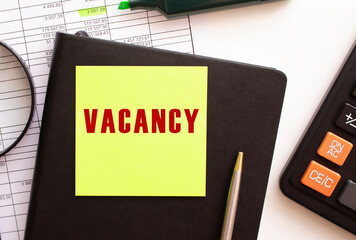 VACANCY text on a sticker on your desktop. Diary, calculator and pen.