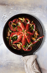 Octopus Lagareiro style dressed with onion and garlics cloves on an aged metallic table. Portuguese cuisine. © Álvaro Germán Vilela