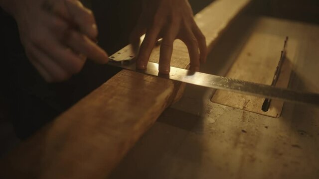 Carpenter checking wood plank's width for making a beautiful piece of furniture in his workshop. High quality 4k footage.