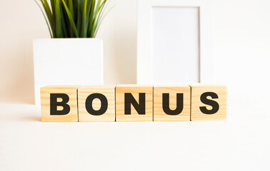 Wooden cubes with letters on a white table. The word is BONUS. White background.