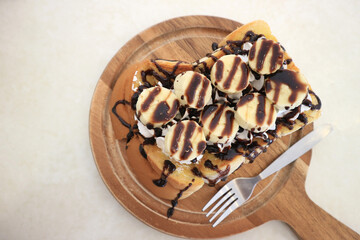 Bread bakery homemade toasted white chocolate and banana on wood plate, top view.