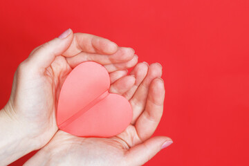 female hands hold a red heart on the palms isolated on a red background. Love, Wedding, Valentines day, 8 March concept.