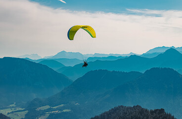 Beautiful alpine summer view with a paraglider and mountain silhouettes in the background at the...