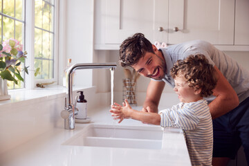 Father Helping Son To Wash Hands With Soap At Home To Stop Spread Of Infection In Health Pandemic - Powered by Adobe