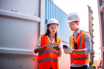 Asian dock control man and woman logistics worker wear safety helmets and protect suite open cargo...