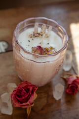 Soya candle with crystal quartz and rose decoration on vintage wooden table