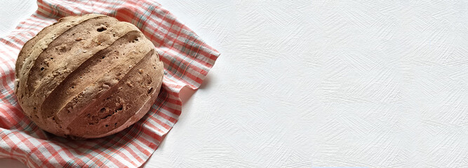 loaf of homemade bread on a checkered towel. banner