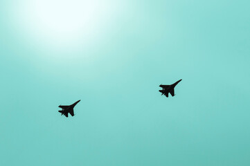 Against the background of a blue sky with a bright sun, a group of two military aircraft.