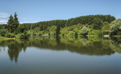 Fototapeta na wymiar Landscape of calm lake in forest, reflections on water