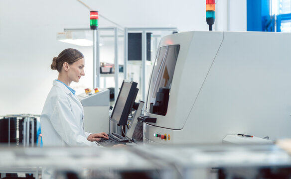 Worker Woman In Factory Operating A Soldering Machine For Electronics Production