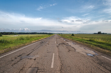 Long driveway in field, rural road, landscape with clouds