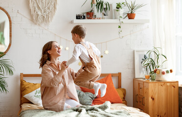 Happy woman and boy playing in bedroom