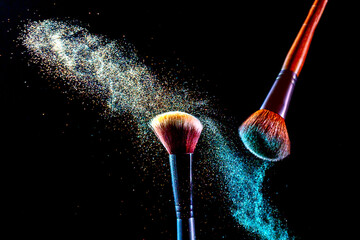 Make up cosmetic brushes with colorful shadows explosion on black background. Skin care or fashion...