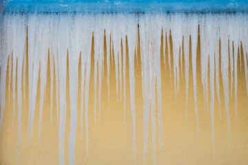 Fototapeta na wymiar gefährliche Eiszapfen an Haus und Dachrinne im Winter gefroren zu Eis