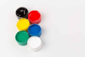 Plastic jars with paint of different colors for children's creativity on white background. Paint bottles for art