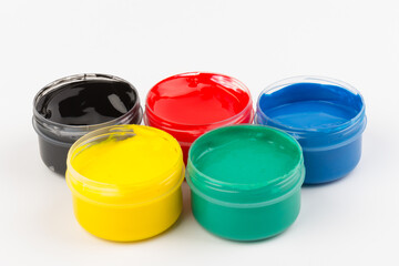 Plastic jars with paint of different colors for children's creativity on white background. Paint bottles for art