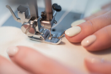 Close-up. A woman works on an electric sewing machine at home