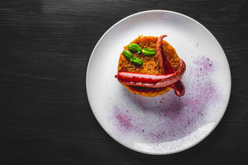 Fried cabbage with sausage in white plate on black wooden table background