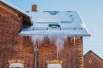 gefährliche Eiszapfen an Haus und Dachrinne im Winter gefroren zu Eis - 414138147