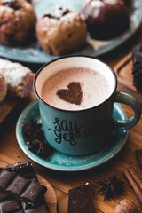 turquoise cup of hot coffee on grey background with cinnamon sticks and christmas decorations