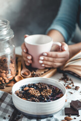 Healthy breakfast, muesli with berries and orange juice served on glass table and books. manicure