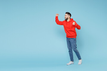 Full length of young caucasian happy bearded overjoyed excited man 20s in casual red orange hoodie...