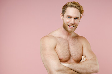 Fototapeta premium Smiling attractive bearded naked young man 20s years old perfect skin holding hands crossed isolated on pastel pink color background studio portrait. Skin care healthcare cosmetic procedures concept.