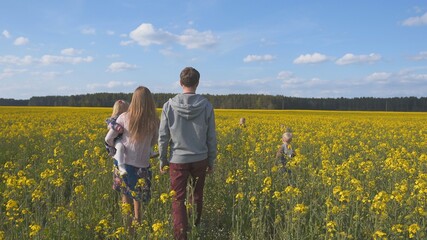 Fototapeta premium A happy family walks on a rapeseed field.