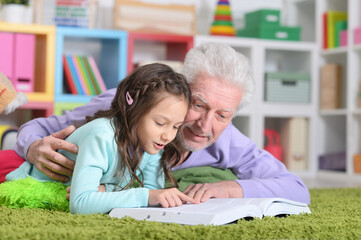 Fototapeta premium little cute girl with grandfather reading book