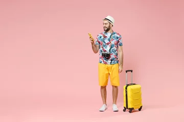 Deurstickers Full length of smiling young traveler tourist man using mobile phone booking hotel taxi isolated on pink color background studio portrait. Passenger traveling on weekends. Air flight journey concept. © ViDi Studio