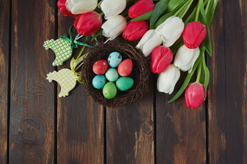 colorful tulips and Easter eggs on brown wooden surface