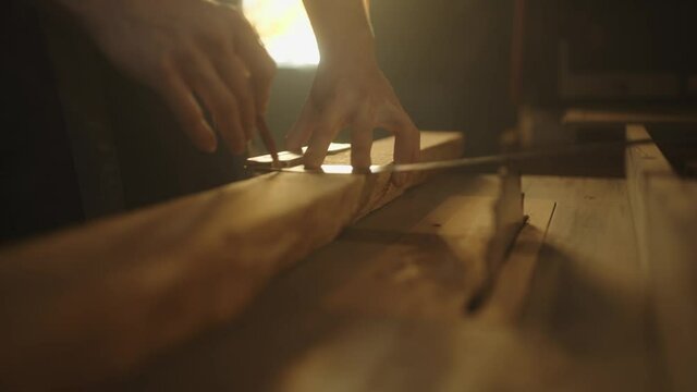 Carpenter checking wood plank's width for making a beautiful piece of furniture in his workshop.
