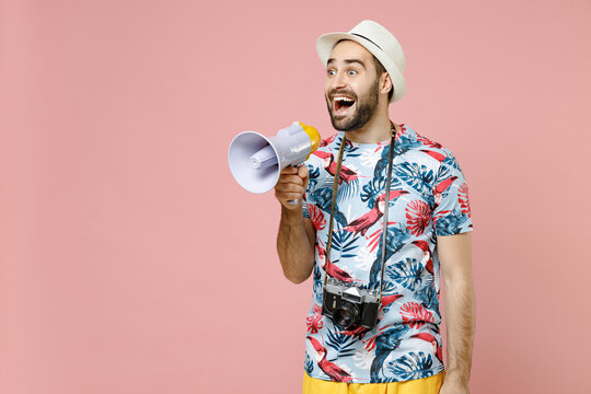 Shocked Young Traveler Tourist Man In Summer Clothes Hat Screaming In Megaphone Looking Aside Isolated On Pink Background Studio Portrait. Passenger Traveling On Weekends. Air Flight Journey Concept.