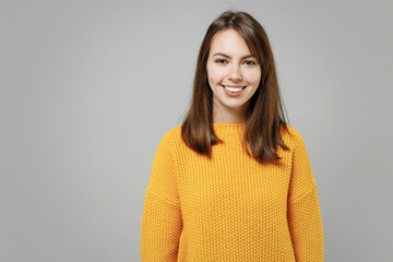 Young smiling pretty happy positive attractive beautiful woman 20s wearing casual knitted yellow sweater looking camera isolated on grey color background studio portrait. People lifestyle concept.