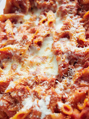 pasta and baked mozzarella cheese in tomato sauce close-up view filling the frame