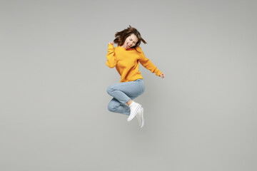 Fototapeta na wymiar Full length of young excited overjoyed happy lucky positive attractive woman 20s wearing knitted yellow sweater do winner gesture clench fist jumping high isolated on grey background studio portrait..