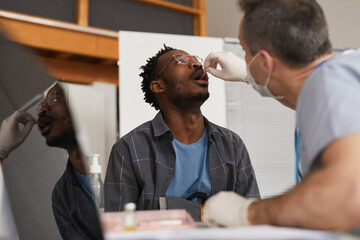 Obraz premium Low angle portrait of young African American man taking covid test in vaccination center or clinic, copy space