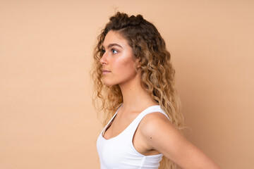 Young blonde woman with curly hair isolated on beige background . Portrait