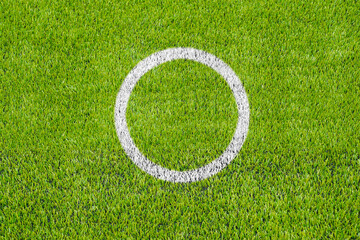 Top view of the white penalty point on the artificial green grass soccer field.