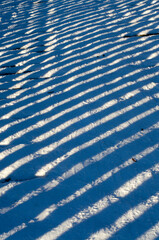 Wooden bridge in winter with snow and shadows lines, background texture