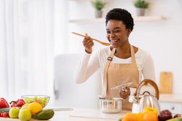 Happy African American Woman Cooking Tasting Dinner In Kitchen Indoor