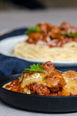 The homemade italian pasta or spaghetti with meatball , cheese and tomato sauce placed in a white dish with on dark blue tablecloth on the table..
